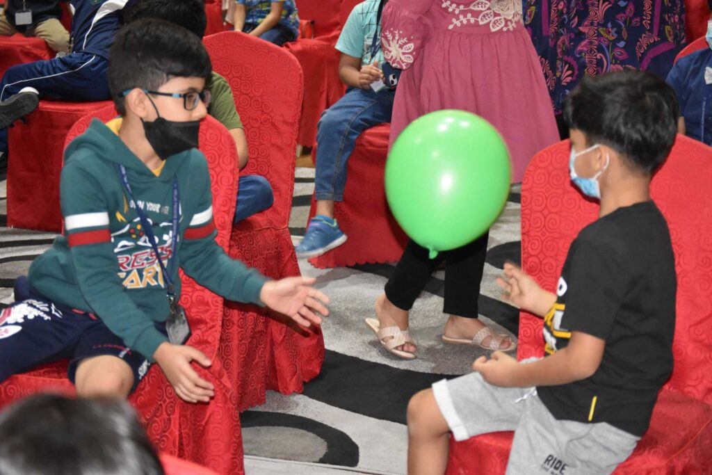 Students playing with balloons in the DPS Ajman auditorium