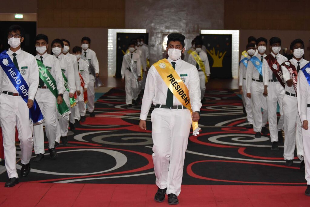 Student leaders in sashes marching in procession at the DPS Ajman investiture ceremony