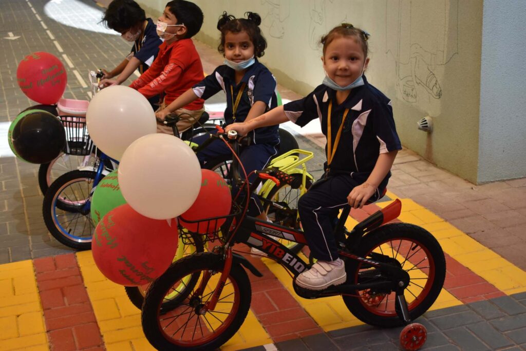 Kindergarten children riding balloon-decorated bicycles at DPS Ajman